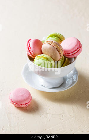 Bunte Cookies Macaron in das weiße Porzellan Tasse auf einem hellen Hintergrund Stockfoto
