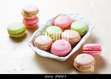 Drei bunte Cookies Macaron auf weißen quadratischen Platte auf hellem Hintergrund Stockfoto