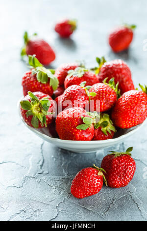 Frische Erdbeeren in Schüssel auf grauem Hintergrund Stockfoto