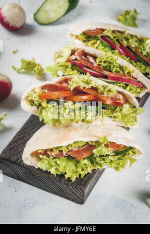 Snack. Speisen zum mitnehmen, Straße Fast-Food. Pita Brot Sandwich mit frischem Gemüse Salat, Gurken, Tomaten, Radieschen, Rindfleisch. Auf einem hellen Beton ta Stockfoto