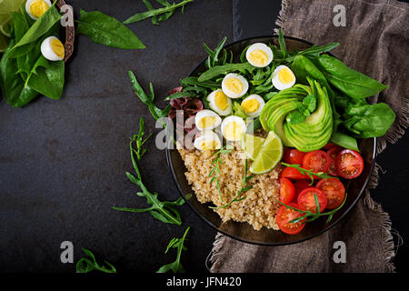 Diät-Menü. Gesunder Salat mit frischem Gemüse - Tomaten, Avocado, Rucola, Ei, Spinat und Quinoa auf Schüssel. Flach zu legen. Ansicht von oben. Stockfoto