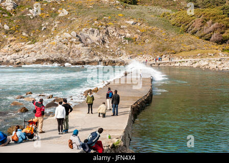 VIGO, Spanien - 7. APRIL: Menschen warten, um den Pfad auf das Meer zu überqueren, ohne nass von der Welle. Aufgenommen am Cies Inseln Naturpark, Galizien, Spanien Stockfoto