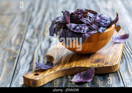 Hölzerne Schüssel mit Blättern von lila Basilikum c Wasser tropfen. Stockfoto