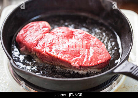 Roh gewürzt Angus Steak gebraten auf Pflanzenöl, Eisen-Guss Stockfoto