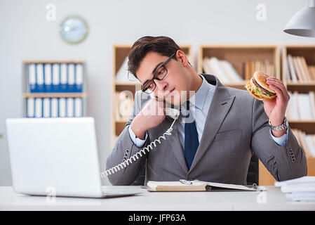 Die hungrigen lustig Geschäftsmann Essen der Trödelnahrung Sandwich Stockfoto