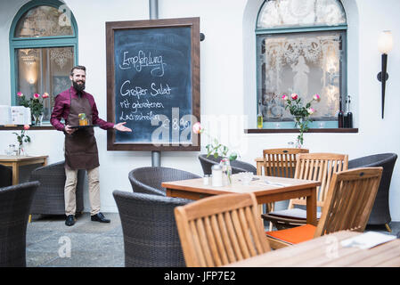 Junger Mann zeigte auf Tafel Menü im restaurant Stockfoto