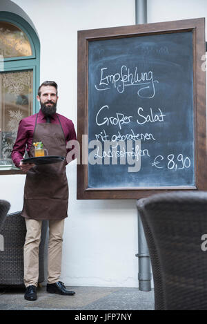 Jungen Kellner Stand Tafel Menü im restaurant Stockfoto