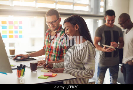 Junge Frau die Notizen mit Kollegen beim Menschen Surfen die Tablette im Büro. Stockfoto