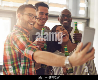 Fröhliche junge Unternehmer im Büro nehmen Selfie mit den Bierflaschen. Stockfoto