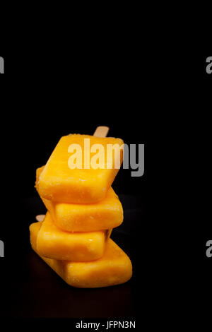 Ananas, Aprikose und Mango-Popsicles auf schwarzem Hintergrund Stockfoto