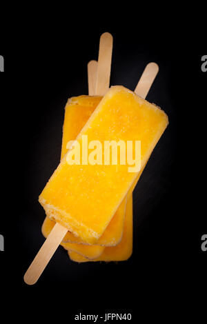 Ananas, Aprikose und Mango-Popsicles auf schwarzem Hintergrund Stockfoto