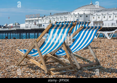 Leere Liegestühle am Strand neben dem berühmten viktorianischen Struktur, Brighton Palace Pier, an einem sonnigen Tag. Stockfoto
