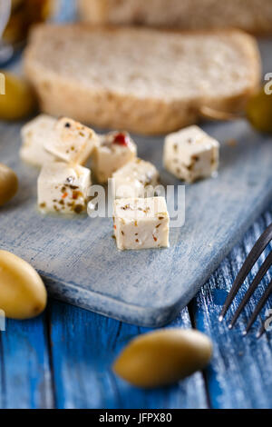 Kleine Käsewürfel auf blauem Hintergrund aus Holz Stockfoto