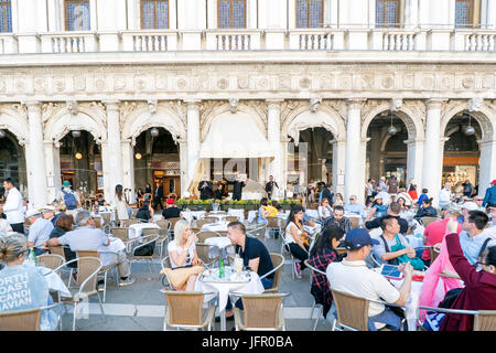 Venedig, Veneto / Italien. 21. Mai 2017: Terrassen mit dem Trinken Menschen und Musiker spielen auf der großen Cafe Chioggia in Piazza San Marco Stockfoto