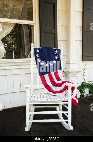 Betsy Ross flag 13 Sterne auf einem Holzschaukelstuhl, historische Bauernhausmöbel vor der Veranda in Freehhold Township, New Jersey, USA, US-Flagge 2017 Stockfoto