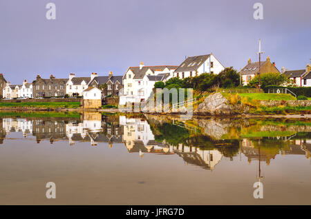 Blick auf Port Ellen Stadthäuser mit Wasserreflexion über Isle of Islay, Schottland, Vereinigtes Königreich Stockfoto