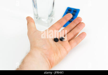 Mannes Hand mit Aktivkohle-Pillen. Stockfoto