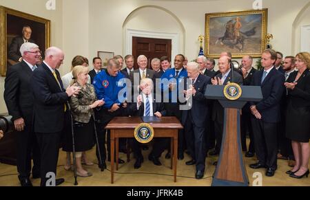 US-Präsident Donald Trump umgeben von Mitgliedern des Kongresses, Astronauten und kommerzielle Raumfahrtunternehmen Zeichen eine Executive Order, Raum Nationalrat im Roosevelt Room des weißen Hauses in Washington, DC 30. Juni 2017 wieder herzustellen. Vizepräsident Mike Pence, wird auch anwesend, den Rat den Vorsitz. Auch abgebildet sind, ehemaliger NASA-Astronaut David Wolf, links, Astronaut Alvin Drew, zweiter von rechts, und ehemaliger NASA Astronaut Legende Buzz Aldrin, rechts. Stockfoto