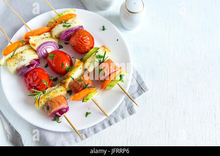 Gegrillte Wurst und Gemüse-Spieße mit frischen Kräutern auf weißen Teller, Textfreiraum Stockfoto