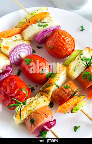 Gegrillte Wurst und Gemüse-Spieße mit frischen Kräutern auf weißen Teller Stockfoto