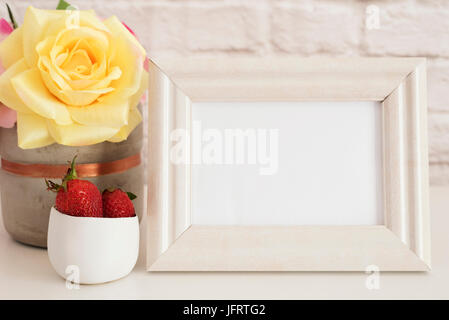 Frame-Mockup. Weißer Rahmen Mock Up. Bilderrahmen, Vase mit rosa Rosen, Erdbeeren In Gold Schüssel Sahne. Produkt-Frame-Modell. Wand Kunst Anzeige Templa Stockfoto