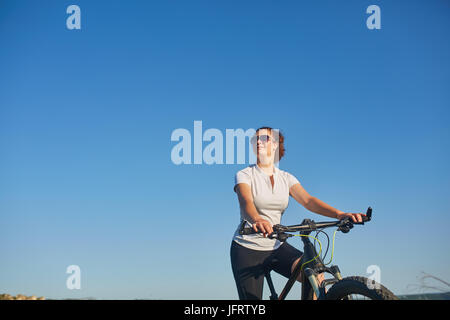 Porträt von gesund Fit und sportlich, selbstbewusst und erfolgreich Reife Frau Radfahren Mountainbike, isoliert mit blauem Himmel als Hintergrund und Kopie spac Stockfoto