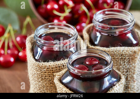 Kirsche Marmelade auf hölzernen Hintergrund in Gläsern Stockfoto