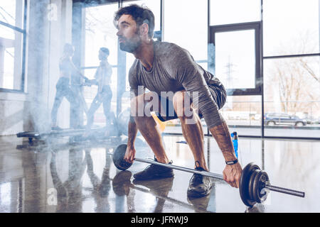 Voller Länge Blick auf muskulöse Sportler heben Langhantel im Fitness-Studio trainieren Stockfoto