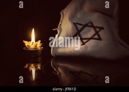 Eine brennende Kerze neben dem Davidstern auf einem schwarzen Hintergrund. Ein Symbol des Gedenkens an die Opfer des Völkermords an den Juden im dritten Reich Stockfoto