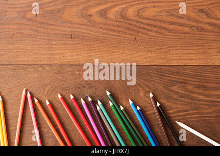 Bunte Bleistifte auf dem braunen Holztisch Hintergrund. Rahmen der Buntstifte über Holz mit freiem Speicherplatz für Text, Textfreiraum Stockfoto