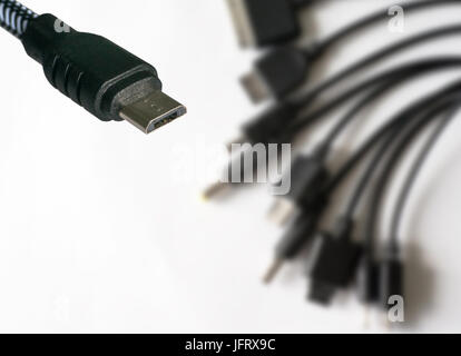Micro USB-Kabel Nahaufnahme. Auf dem Hintergrund der einiges an verschiedene Ladegeräte für ältere Handys. ein Ladegerät für alle Handys Stockfoto