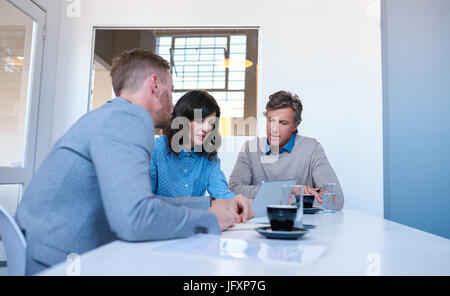 Mitarbeiter, die mit einem digitalen Tablet zusammen in einem Büro konzentriert Stockfoto