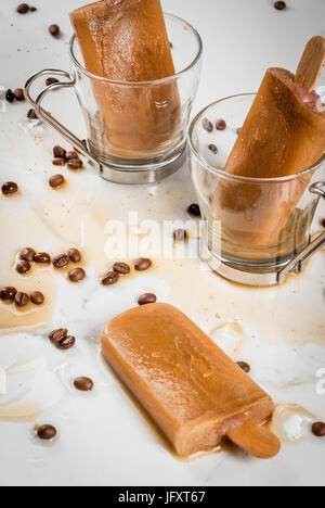 Sommer Desserts. Frozen Drinks serviert. Süße Eis am Stiel aus Kaffee und Milch hergestellt. In Kaffeetassen, auf einem weißen Marmortisch mit Kaffeebohnen. Textfreiraum Stockfoto