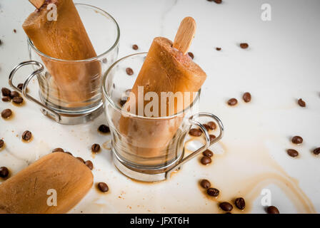 Sommer Desserts. Frozen Drinks serviert. Süße Eis am Stiel aus Kaffee und Milch hergestellt. In Kaffeetassen, auf einem weißen Marmortisch mit Kaffeebohnen. Textfreiraum Stockfoto