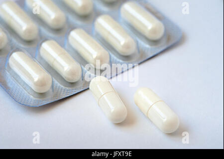 Auf einem weißen Tisch liegen zwei weiße Pillen. Verpackung-Tabletten in den Hintergrund. Konzept von Gesundheit, Medizin, Pharmakologie Stockfoto