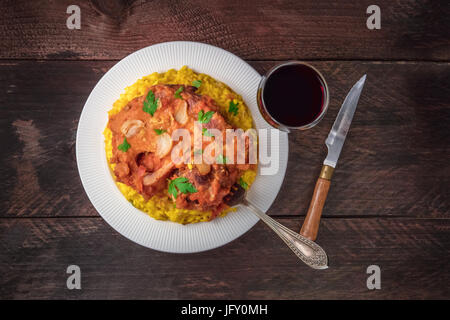 Foto von Ossobuco, traditionelles italienisches Gericht serviert mit Risotto Alla Milanese, Safranreis und Gremolata, geschossen von oben auf die rustikale Textur mit gl Stockfoto