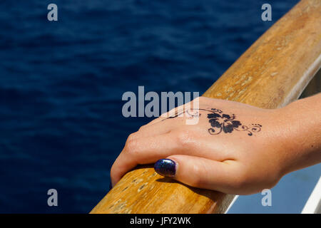 Ein Foto von einer weiblichen Hand hält auf den Handlauf von einem Boot im Mittelmeer, Malta. Es gibt eine florales Design Henna-Tattoo auf dem Rücken o Stockfoto