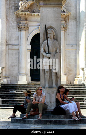 DUBROVNIK/Kroatien - 28. Juni 2017: Touristen sitzen in den Schatten unter Orlandos Colum vor der venezianischen Barock Kirche von Saint Blaise, Prot Stockfoto