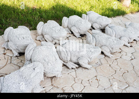 Kalkstein Statuen von Fröschen. Stein Weg. Frösche auf Gasse im wunderschönen Garten mit Blumen und Bäumen. Sommer im Garten Stockfoto