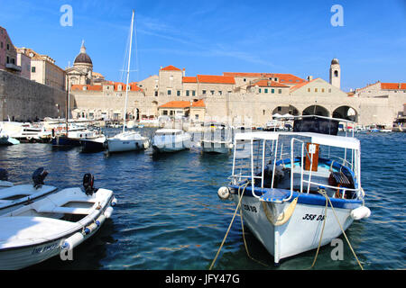 DUBROVNIK/KROATIEN - 28. JUNI 2017: Lokale Boote, die im kleinen Hafen der Altstadt von Dubrovnik geparkt sind, befinden sich direkt an den Stadtmauern Stockfoto