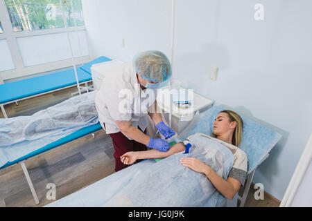 Krankenschwester macht eine Injektion mit einer Frau am OP-Tisch am Klinikum Vorbereitung Narkose medizinische Arztpraxis Konzept liegen. Stockfoto