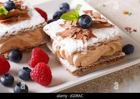 Schönes Dessert: Schokoladenkuchen mit Kaffee-Creme, Himbeeren und Heidelbeeren Nahaufnahme auf einer Platte. horizontale Stockfoto