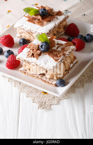 köstliche Schokolade Millefeuille mit Himbeeren und Heidelbeeren Nahaufnahme auf einer Platte. Vertikal Stockfoto