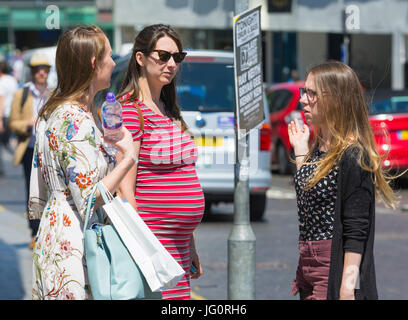 Schwangere Frau stehend in einer Stadt im Gespräch mit Freundinnen. Stockfoto