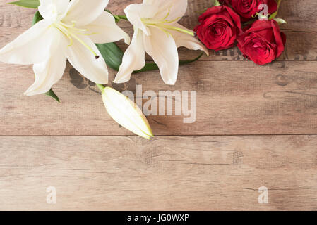 Blumenrahmen mit herrlichem weißen Lilien und Rosen auf hölzernen Hintergrund. Kopieren Sie Raum. Hochzeit, Geschenkkarte, Valentinstag oder Muttertag Tag Hintergrund Stockfoto