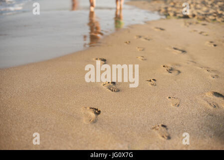 Fußspuren im Sand. Menschliche Fußabdrücke führt vom Betrachter weg. Eine Reihe von Fußspuren im Sand am Strand im Sommer. Sommer Urlaub Stockfoto