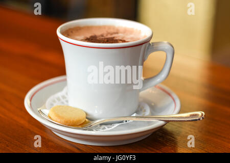 Heißer Schokolade in eine weiße Tasse mit einem Löffel und Keks hautnah Stockfoto