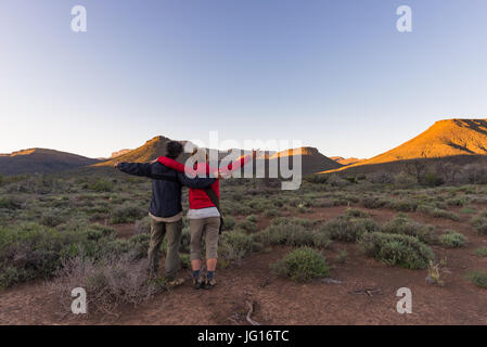 Knuddeln paar mit ausgestreckten Armen die atemberaubende Aussicht von der Karoo-Nationalpark bei Sonnenuntergang beobachten, Reiseziel in Südafrika. Reisen p Stockfoto