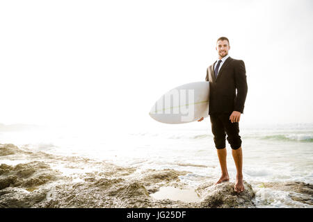 Der Unternehmer hält ist Surfbrett nach einem langen Tag der Arbeit Stockfoto