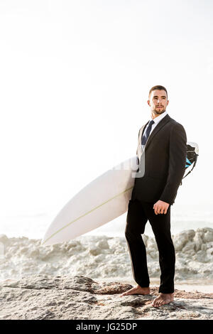 Der Unternehmer hält ist Surfbrett nach einem langen Tag der Arbeit Stockfoto